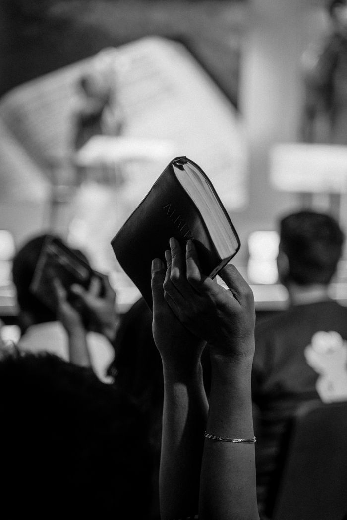 heros-img Monochrome image of a religious congregation in Jakarta, Indonesia, with raised Bibles.